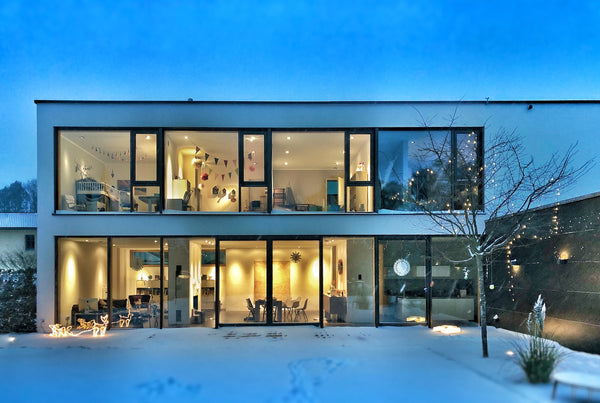 outside view a modern glass home surrounded by snow
